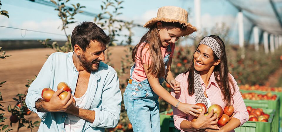 Diverse group of male and female farmers in casual attire smiling together in a vibrant agricultural field